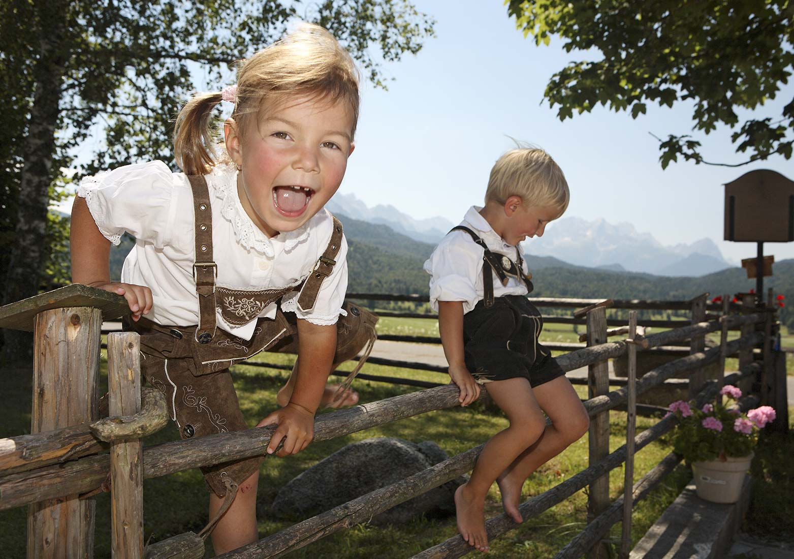 Das kleine Mädchen fühlt sich in Lederhosen sehr wohl und klettert wagemutig über den Holzzaun | NIKKY MAIER photo - 12