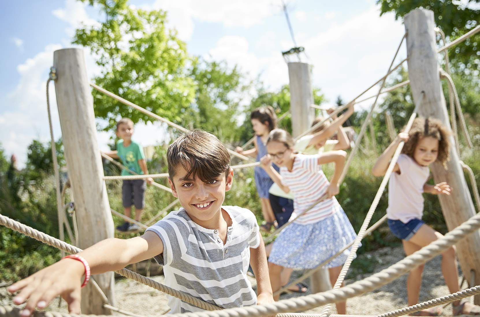 Eine Gruppe von Kindern klettern zwischen den Seilen auf dem Spielplatz in Augsburg - NIKKYMAIER photo - 02